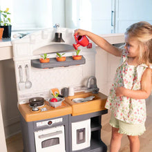 Toy play kitchen set with sink and stove; child reaches for red pot