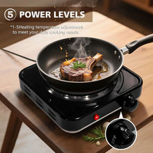 Black electric hot plate with coil burner, cooking steak in a frying pan