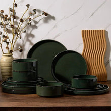Ceramic dinnerware set with dark green bowls and plates, terracotta plates