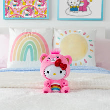 Pink cheer bear plush with red bow and rainbow belly, sitting on soft bedding