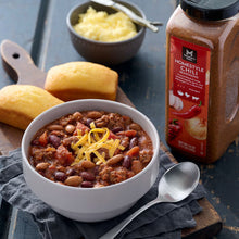 Member's Mark Homestyle Chili Seasoning bottle beside a bowl of chili topped with cheese.