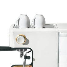 White espresso machine head with gold control knob and steam wand, close-up