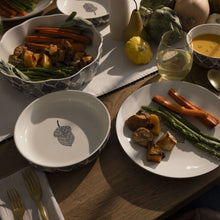 Stoneware low bowls with gray leaf print on cream, shown with food