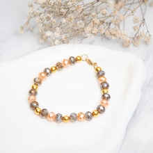 Beaded bracelet with faceted gold-tone beads and clasp, on a white dish
