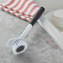 Angled sink brush with rounded white scrubbing head and black soft-touch handle