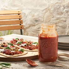 Glass mason jar with metal lid, filled with red sauce