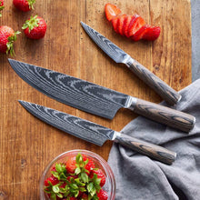 Stainless Damascus knives with dark wood handles resting on wooden board with strawberries