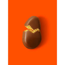 Milk chocolate peanut butter egg with bite showing golden peanut filling