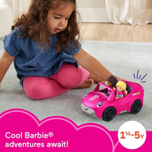 Toy convertible car with two seated dolls next to a child playing