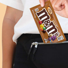 Hand holding a caramel cold brew M&M's candy pack over a person in a white shirt