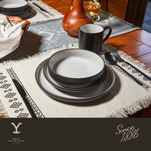Ceramic dinnerware set with stacked white plates and black rims on a table setting