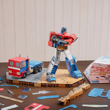 Assembled red and blue robot figure with truck kit parts on wooden base