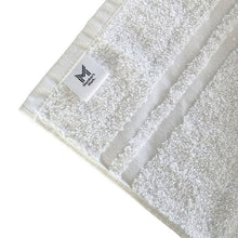 White bath towel with woven surface and attached brand label tag