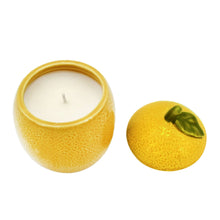 Yellow ceramic lemon fruit candle with open top and lit wick, matching lid