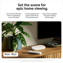 Streaming media streamer and voice remote, light gray, shown with devices on a table.
