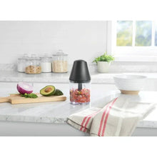 Electric food chopper on counter with black lid and clear cup