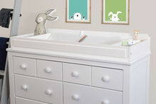 White contoured diaper changing pad on dresser with built-in safety rail