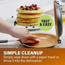 Orange double-sided pancake pan being wiped clean with a cloth