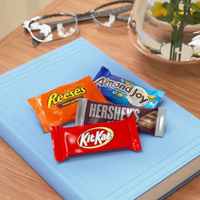 Snack-size chocolate bars: Hershey's, Reese's, KitKat, AlmondJoy on blue paper