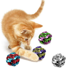 Orange kitten playing with multicolor mylar crinkle balls on a white surface