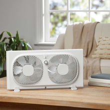 White dual window fan on a wooden table with two circular fan grills
