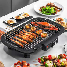 Electric smokeless grill with prawns and seafood on the cooking rack, black base.