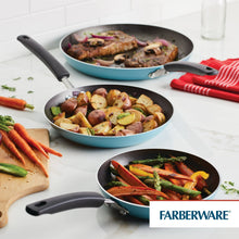 Three aqua nonstick frying pans on a kitchen counter with cooked food and vegetables