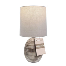 Ceramic table lamp with beige shade and tag attached to the base