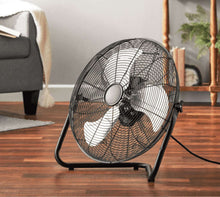 Black steel floor fan on base with round grille and central motor hub