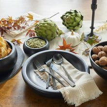 Black stainless steel flatware set with forks, knife, and spoons on plate