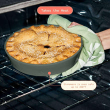 Green stoneware baker holding baked pastry with towel