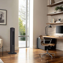 Black tower fan on the floor beside a workspace area