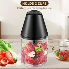 Electric food chopper filling with chopped red and green ingredients in clear cup