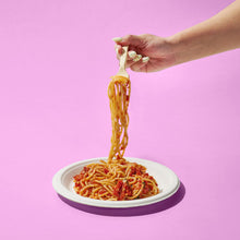 Beige compostable fork lifting spaghetti from a plate