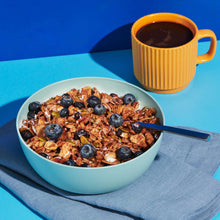 Blueberry cinnamon nut granola bowl with blueberries and spoon, plus coffee mug