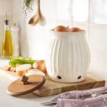 White onion keeper on wooden board with ridged stoneware body and wooden knob lid