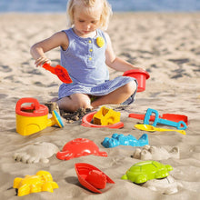 Toddler playing on beach with dinosaur sand molds and sand tools in red and yellow