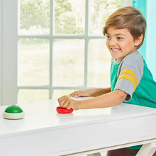 Child playing hover shell strike, pushing a red dome shell on the tabletop