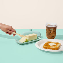 Beige compostable knife spreading butter beside toast and a drink