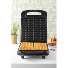 Black 4-slice waffle maker with open baking grids, showing square waffle pattern