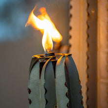 Metal cactus torch burner with flame rising from the carved top
