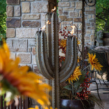 Metal cactus torch sculpture with carved ribs and visible flame at the burner top