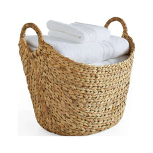 Natural woven water hyacinth boat storage basket holding folded towels