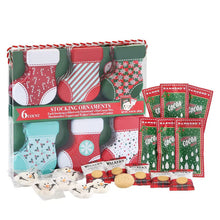 Stocking ornament gift set with six patterned stockings, cocoa packets, cookies, and snowman marshmallows.