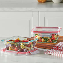 Glass meal prep container with red lid beside glass dish on kitchen counter