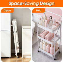Foldable white 3-tier utility cart with lockable wheels, fully extended beside cabinet.