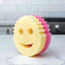 Dual-sided scrub cleaning sponge with yellow foam and pink scrubber top in face shape
