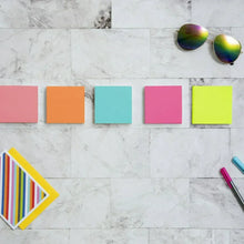Sticky notes, assorted bright square sheets laid out on a light surface