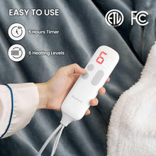 Gray heated throw blanket with white sherpa edge, shown with a handheld controller remote.