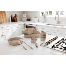 Taupe ceramic bakeware set on countertop, with rectangular baker, ramekins, and utensils